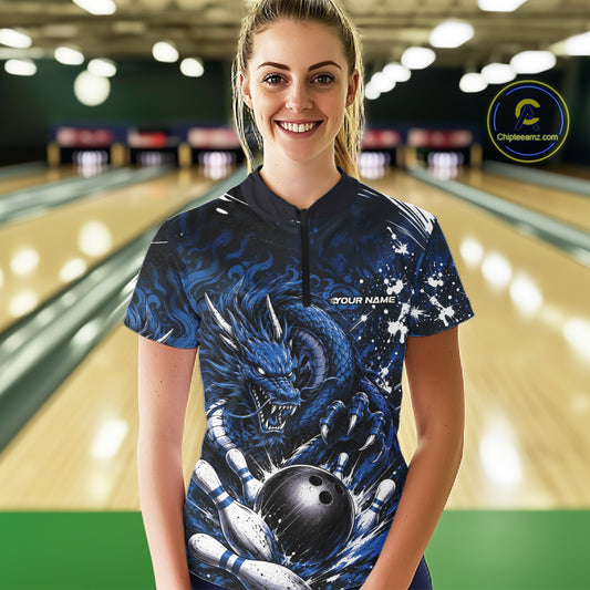 Woman wearing a blue dragon-themed bowling shirt in a bowling alley.