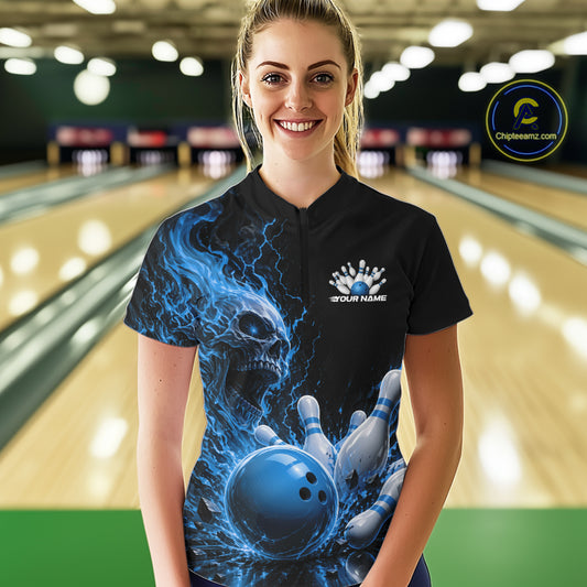 Front view of a female model in a bowling alley wearing a black quarter zip bowling shirt with a blue flaming skull, lightning, bowling pins, and a custom name.