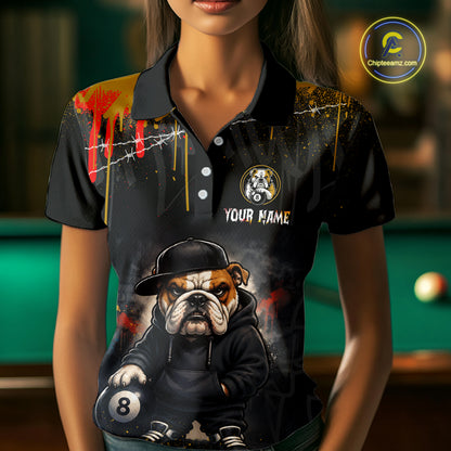A front view of a custom blue and yellow billiards polo shirt worn by a female model . The shirt features  a cartoon hip hop bulldog and an 8-ball on the front. A 'YOUR NAME' text placeholder . The background is a blurred billiards room with a green pool table.
