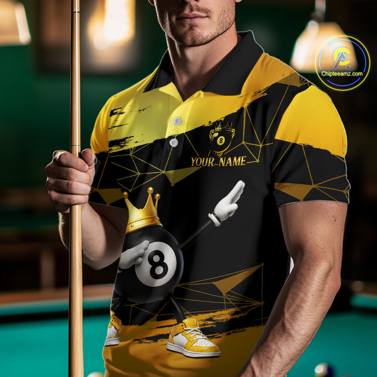 Man wearing custom black and gold geometric crown 8 ball billiard polo shirt standing at a pool table holding a cue stick in a billiard room