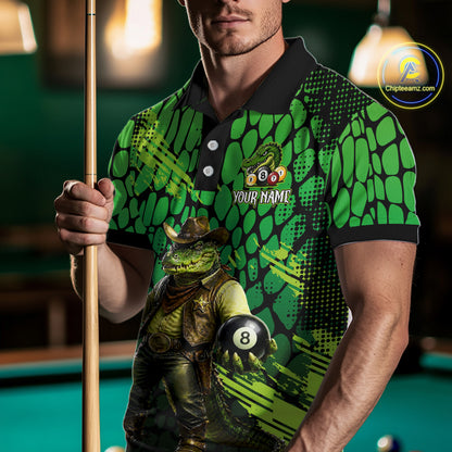 Person wearing a green and black patterned shirt with a crocodile graphic, holding a pool cue and 8-ball on a pool table.