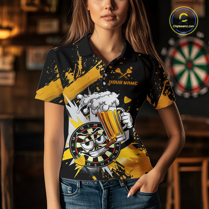 A woman wearing a black short-sleeve polo shirt with a bold yellow and white graphic print featuring a cartoon beer mug, dartboard, and splatter details. The shirt has placeholder text 'YOUR NAME' on the chest.