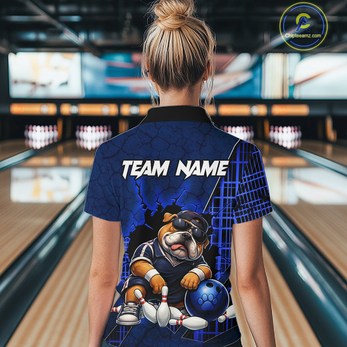A man wearing custom blue bulldog bowling polo shirt back view featuring a bowling ball and blue grid pattern, displaying Team Name, at the bowling alley