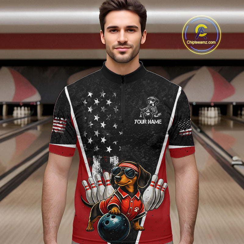A man wearing a custom short-sleeve bowling-themed quarter-zip jersey in a bowling alley setting. The jersey features a black upper section with a white American flag star pattern, red lower sections, and a cartoon dachshund bowling graphic on the front with the text 'YOUR NAME'.