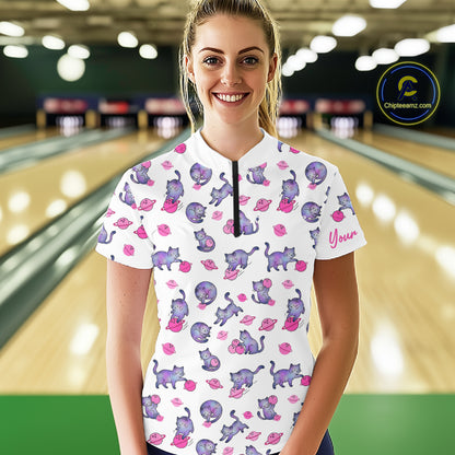 Woman wearing a white bowling shirt with pink cat pattern in a bowling alley.