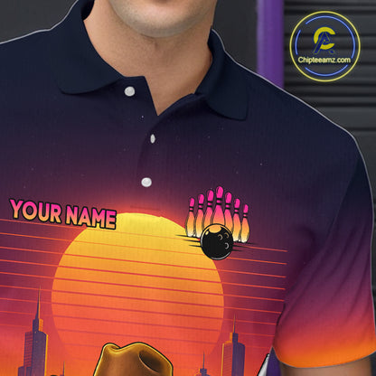 A close-up of a person wearing a dark navy polo shirt with a colorful retro bowling graphic on the front. The design features a large yellow-orange sun, pink bowling pins, a black bowling ball, and the text 'YOUR NAME' in pink.