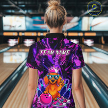 Load image into Gallery viewer, Woman wearing a black and purple bowling polo shirt featuring a cartoon dachshund wearing sunglasses and a crown, holding a pink bowling ball, with custom team name text.
