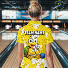 Load image into Gallery viewer, Woman wearing a yellow bowling-themed shirt with a cartoon turtle holding a bowling ball and pins in a bowling alley.