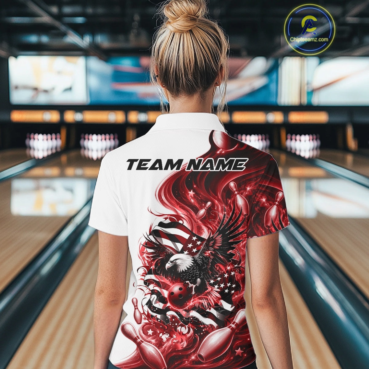 Back view of a female model in a bowling lane wearing a white and red quarter zip shirt with eagle artwork and flag inspired accents.