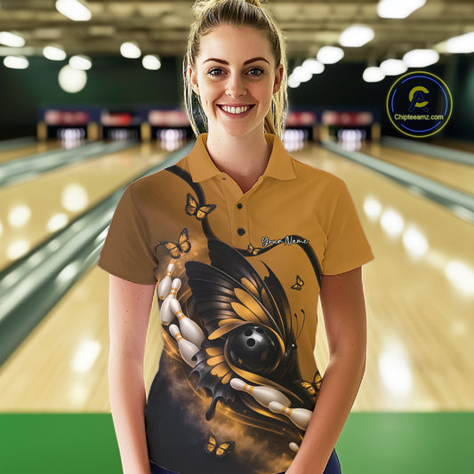 Female model wearing a yellow and black bowling polo shirt at a bowling lane with butterfly artwork, a bowling ball, and bowling pins.