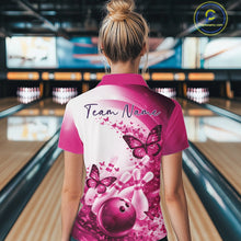Load image into Gallery viewer, Female model in a pink bowling polo with butterfly graphics and bowling artwork, back view inside a bowling alley