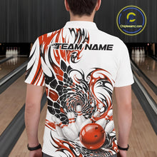 Load image into Gallery viewer, Back view of a male model wearing a white bowling polo shirt with orange and black tribal graphics and a glossy red bowling ball striking pins