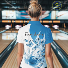 Load image into Gallery viewer, Back view of a female model in a white and blue bowling polo with butterfly graphics and bowling artwork at the bowling lane