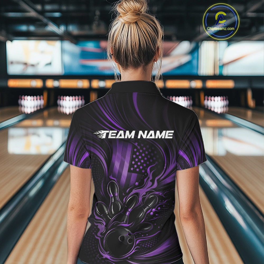 Back view of a female model in a bowling center wearing a black and purple quarter-zip shirt showcasing a flaming bowling ball and patriotic pin motif.