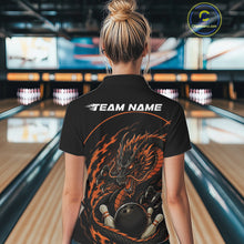 Load image into Gallery viewer, Back view of a female model in a bowling alley wearing an orange custom bowling polo shirt featuring an aggressive dragon with flames in a dynamic and energetic design.