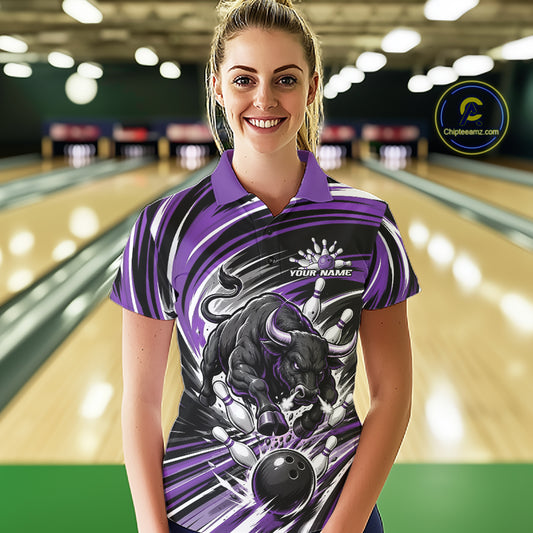 A woman stands in a bowling alley wearing a custom purple and black short-sleeve polo shirt with a bull graphic and the text 'YOUR NAME'. 