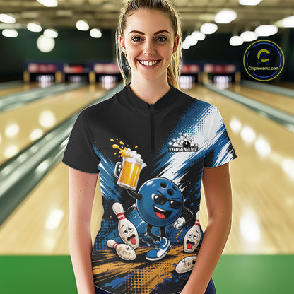 A woman stands in a bowling alley wearing a custom short-sleeve bowling t-shirt. The shirt features a black collar and upper chest, transitioning into a blue and white graphic design with a cartoon bowling ball character, bowling pins, and a beer mug.