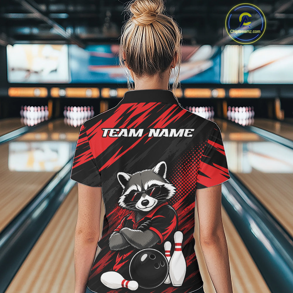 A woman viewed from behind wearing a black and red bowling-themed short-sleeve quarter zip shirt with a raccoon graphic and 'TEAM NAME' text, standing in a bowling alley.