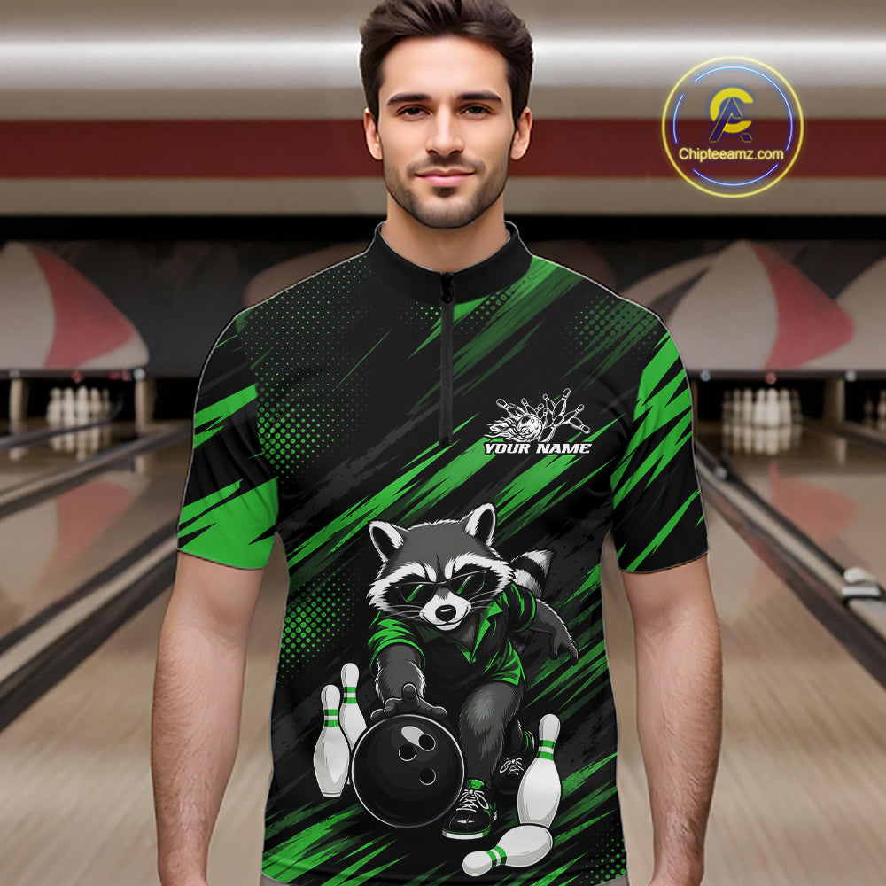 A man modeling a short-sleeve quarter-zip bowling shirt with a raccoon and bowling ball graphic on a black and green background, set against a bowling alley scene.