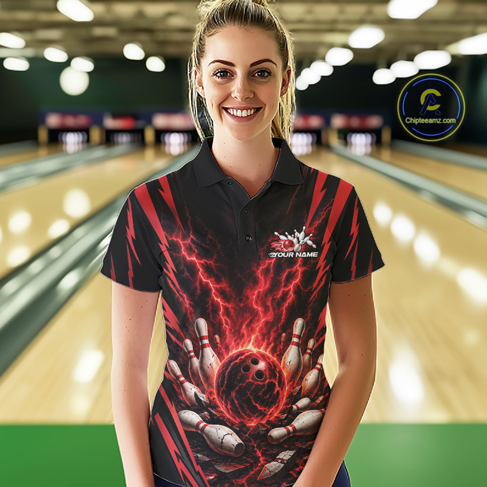 A woman stands in a bowling alley wearing a black short-sleeve polo shirt with a red and black lightning-bolt bowling graphic and a white 'YOUR NAME' placeholder logo on the chest. 