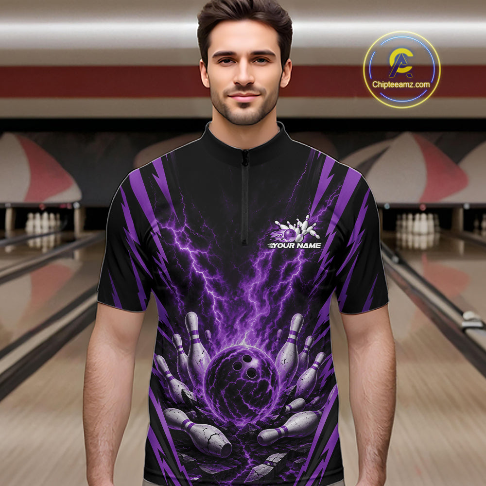 A man wearing a black short-sleeve bowling quarter zip shirt with a purple lightning-bolt and bowling pins graphic, standing in a bowling alley.