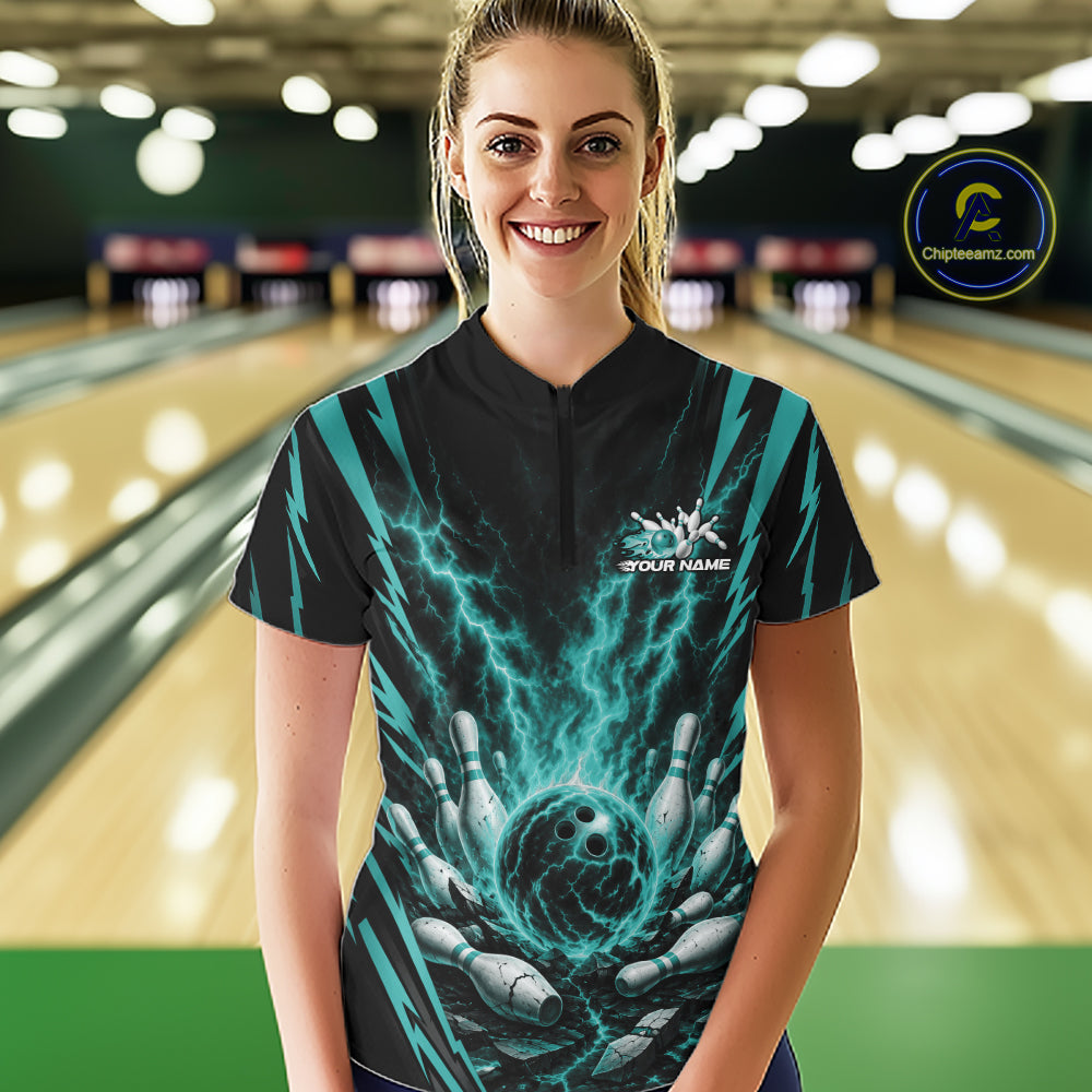 A woman stands in a bowling alley wearing a custom short-sleeve bowling  quarter zip shirt bowling jersey with a black and teal graphic design of lightning and bowling pins. 