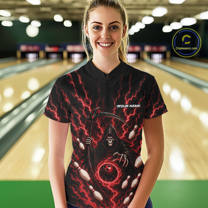 A woman stands in a bowling alley wearing a black short-sleeve bowling quarter zip shirt with a red and black grim reaper graphic, white bowling pins, and a white 'YOUR NAME' text on the chest.