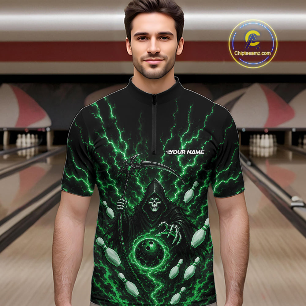 A man wearing a black short-sleeve quarter zip shirt with a green lightning-bolt and grim reaper graphic, standing in a bowling alley. The shirt has 'YOUR NAME' printed on the chest