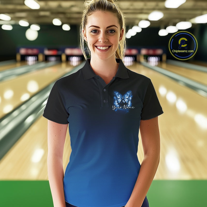 Female model at a bowling lane wearing a blue bowling polo shirt with glowing butterflies, a bowling ball centerpiece, and fallen pin graphics.
