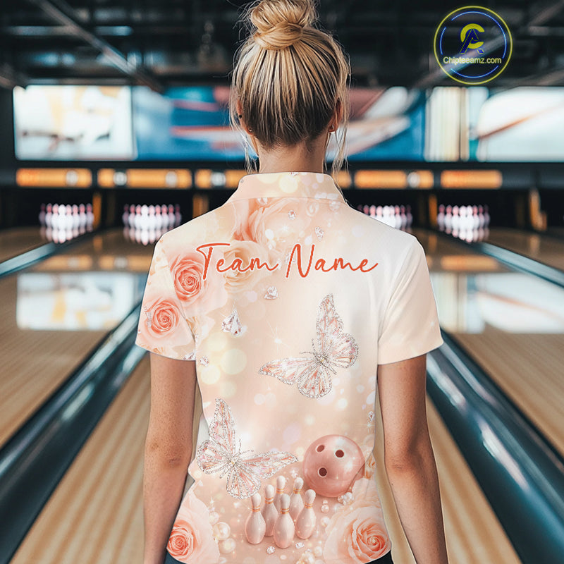 Back view of a female model at a bowling lane wearing a polo shirt showcasing pastel butterflies above bowling pins and bowling ball graphics.