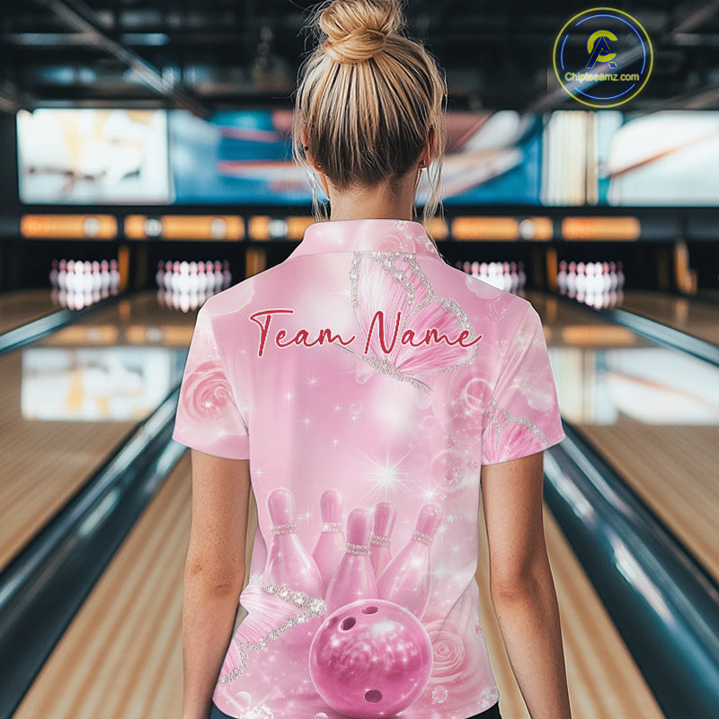 Back view of a female model in a bowling alley wearing a bowling polo shirt featuring pink glitter butterflies and bowling-themed graphics.