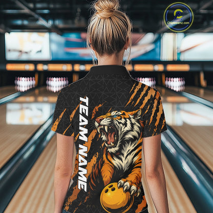 Back view of a female model wearing a black and yellow bowling quarter-zip shirt in a bowling lane, featuring a roaring tiger holding a yellow bowling ball with orange claw-stripe graphics and a geometric background pattern.