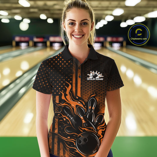Female model at a bowling lane wearing a black and orange bowling polo shirt with fiery bowling strike artwork and patriotic details.