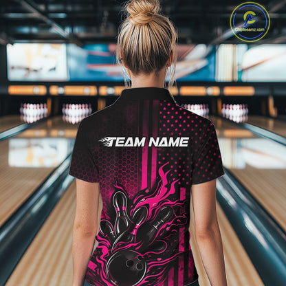 Back view of a female model in a bowling center wearing a black and pink quarter-zip shirt featuring a flaming bowling ball knocking down pins.