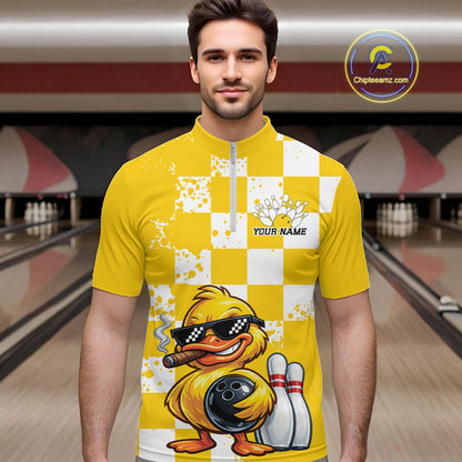 A man wearing a yellow and white checkered bowling-themed quarter-zip shirt with a cartoon duck graphic, set against a blurred bowling alley background. A 'Chipeezm.
