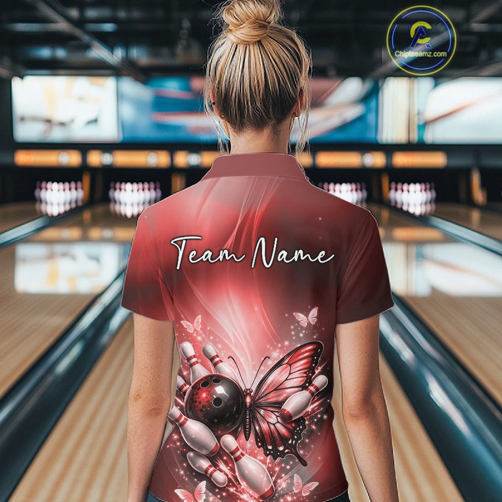 Back view of a female model in a bowling center wearing a red polo shirt featuring a butterfly beside a bowling ball and bowling pins.