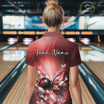 Back view of a female model in a bowling center wearing a red polo shirt featuring a butterfly beside a bowling ball and bowling pins.