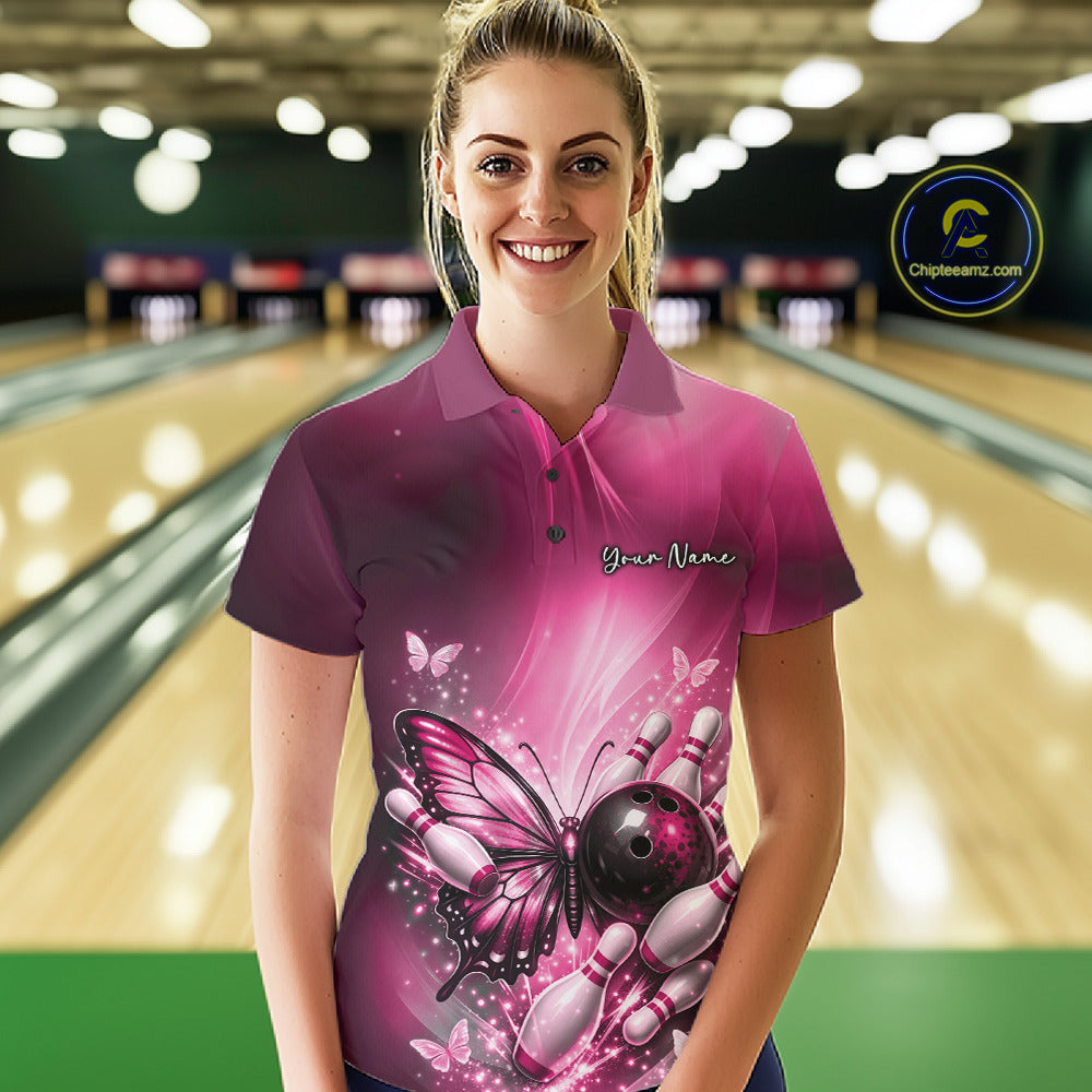 Female model at a bowling lane wearing a pink bowling polo shirt with butterfly artwork, a bowling ball, and scattered pin accents.