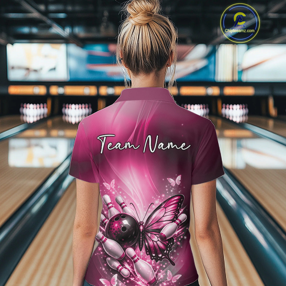 Back view of a female model in a bowling venue wearing a pink polo shirt featuring a butterfly beside a bowling ball and pins.