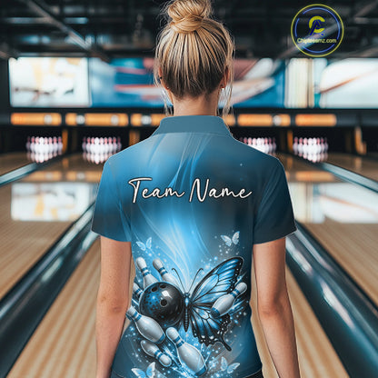 Back view of a female model in a bowling center wearing a blue polo shirt featuring a butterfly beside a bowling ball and bowling pins.