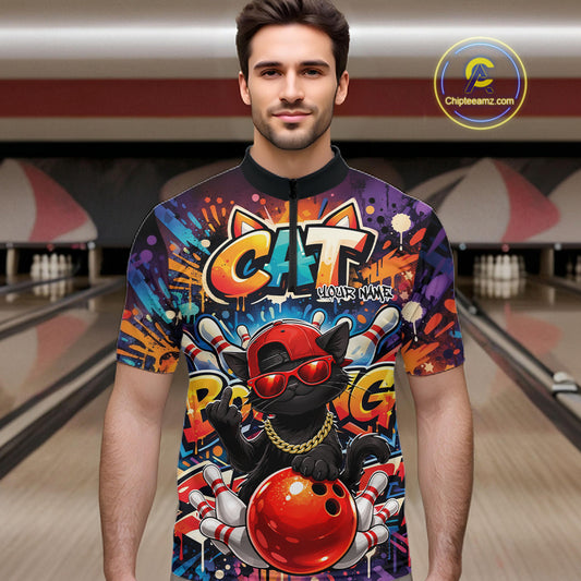 Male model at a bowling lane wearing a colorful quarter-zip bowling shirt with graffiti-style black cat artwork, sunglasses, cap, and bowling ball graphics.