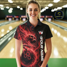 Load image into Gallery viewer, Female model wearing a black bowling polo shirt in a bowling alley featuring a skull clutching a bowling ball engulfed in swirling red energy flames