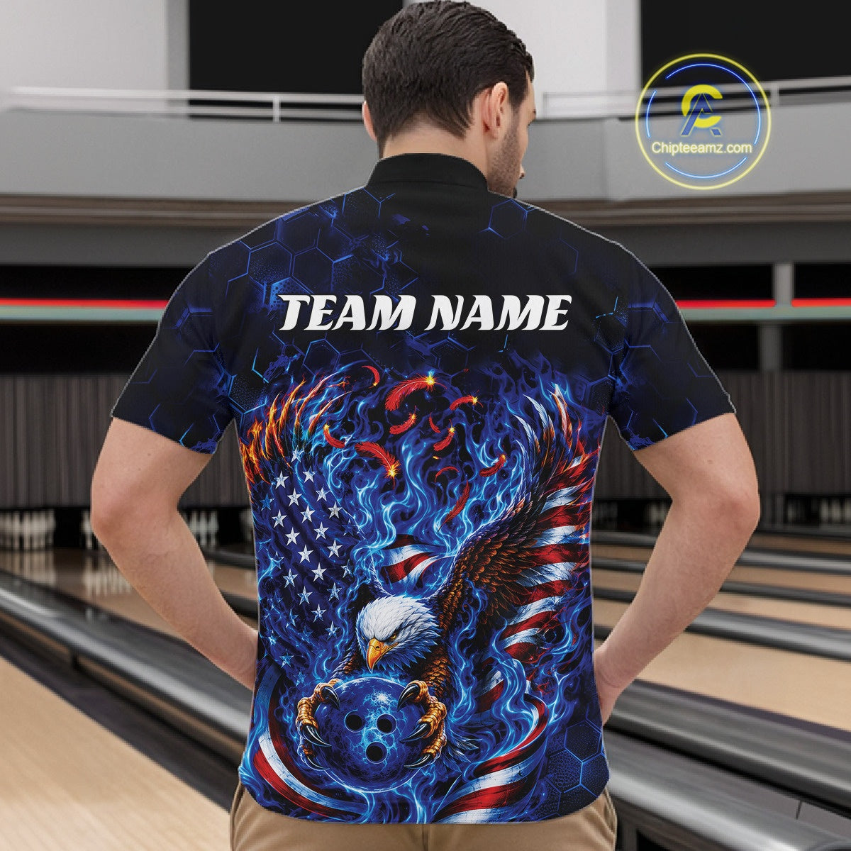Front view male model in a bowling lane wearing a quarter zip shirt with flaming eagle graphics, blue bowling ball, American flag, and blue flames.