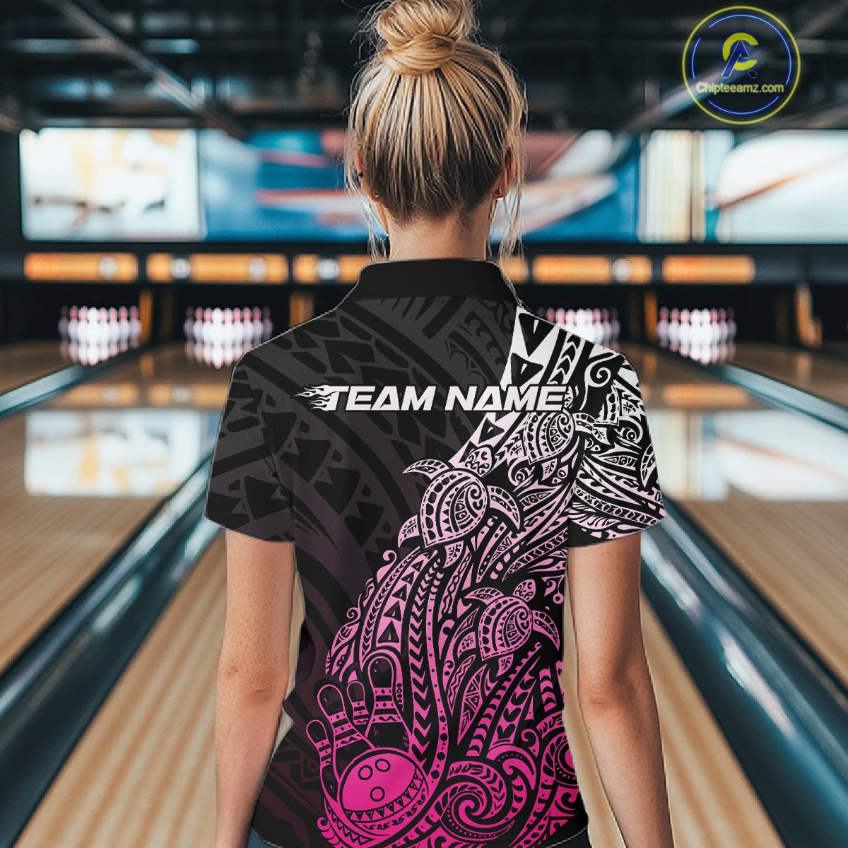 Back view of a female model in a black and pink bowling quarter-zip shirt featuring tribal swirl accents and bowling motifs.