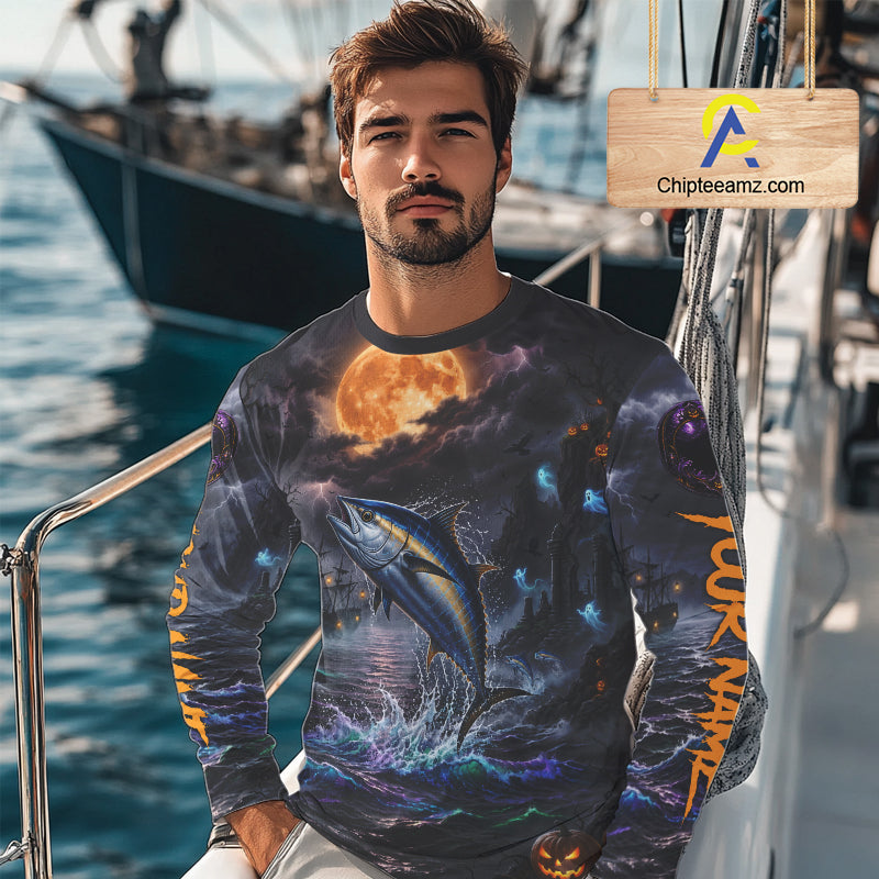 A man wearing a long-sleeve graphic shirt with a detailed print of a tuna fish leaping from the water under a full moon, set on a boat deck. A wooden sign with the text 'Chipleeamz.