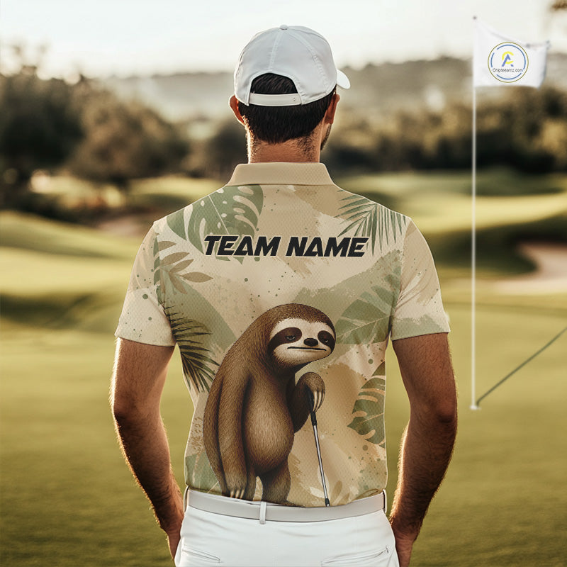 A man viewed from behind on a golf course, wearing a short-sleeve polo shirt with a tropical leaf print and a large sloth graphic on the back. The shirt has 'TEAM NAME' printed across the upper back, and the background shows blurred green fairways with a flagstick and a small logo on the right.