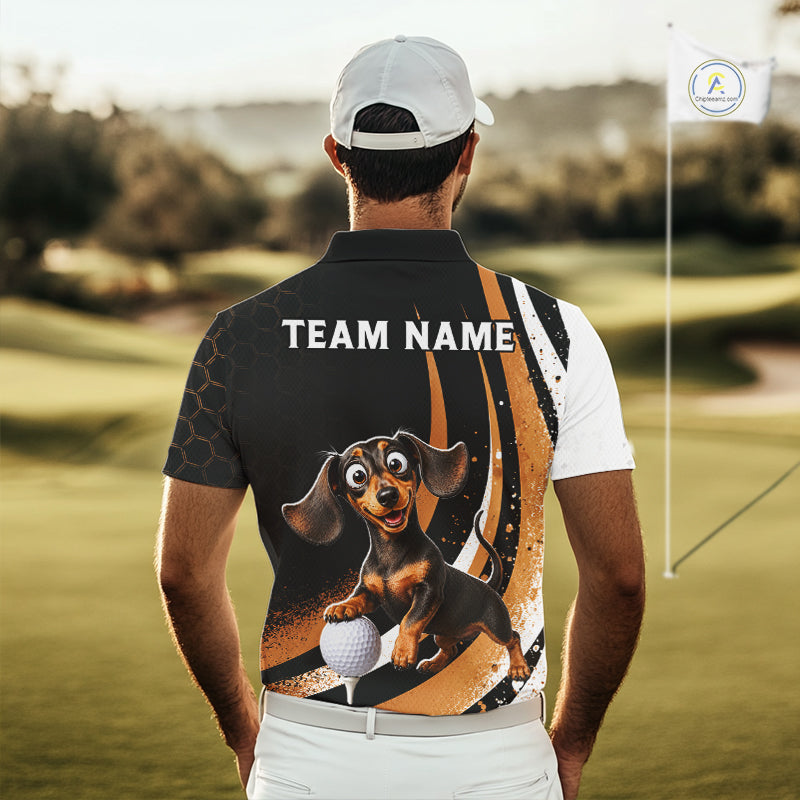 A man on a golf course seen from behind, wearing a custom-printed polo shirt. The back of the black and white polo features a cartoon dachshund holding a golf ball, the text 'TEAM NAME', and a gold abstract graphic.