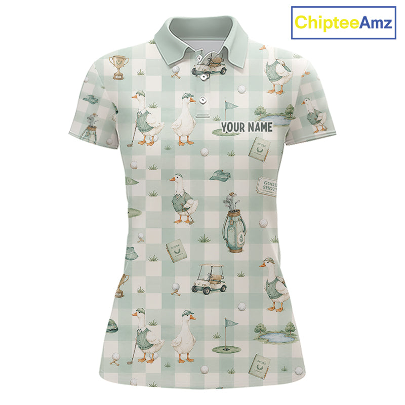 A women's short-sleeve polo shirt with a golf-themed print featuring ducks, golf carts, flags, and a gingham pattern in pale green and white. The shirt has a light green collar and the text 'YOUR NAME' printed on the chest, indicating personalization.