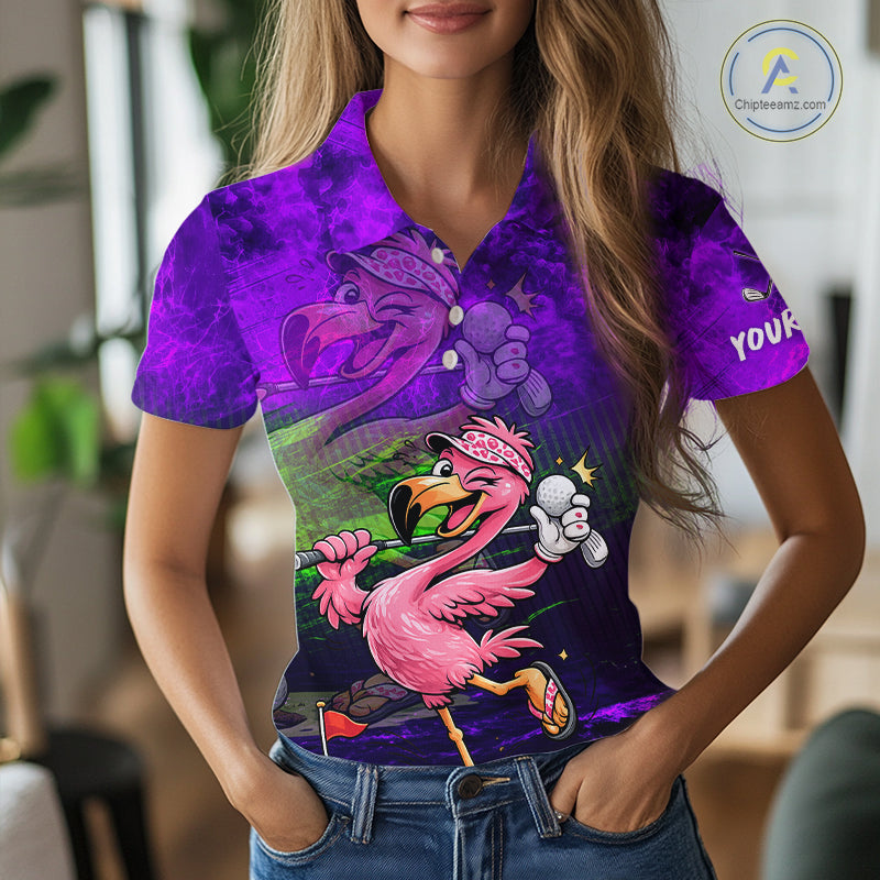 A woman wearing a short-sleeve collared button-up shirt with a vibrant purple and pink flamingo graphic print, paired with blue jeans in a blurred indoor setting.