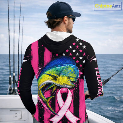 A man on a boat wearing a black and pink fishing hoodie with a large marlin graphic, pink awareness ribbon, and American flag pattern on the back. The hoodie has 'YOUR NAME' printed on the sleeve.